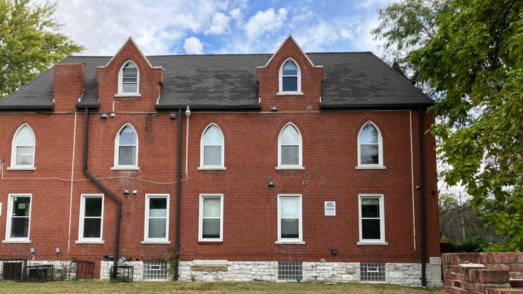 Three story red brick building with 13 white windows